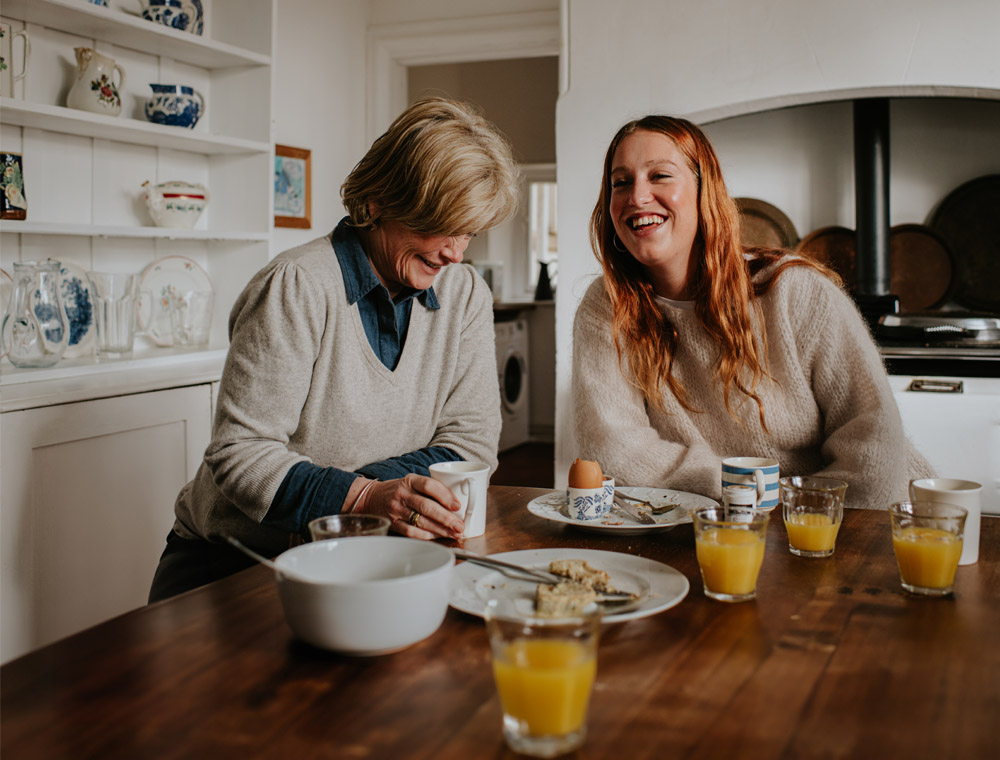 Two women enjoy breakfast together in the kitchen.