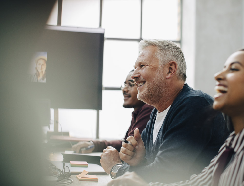 A group of people laughing together at a conference table during a business meeting.
