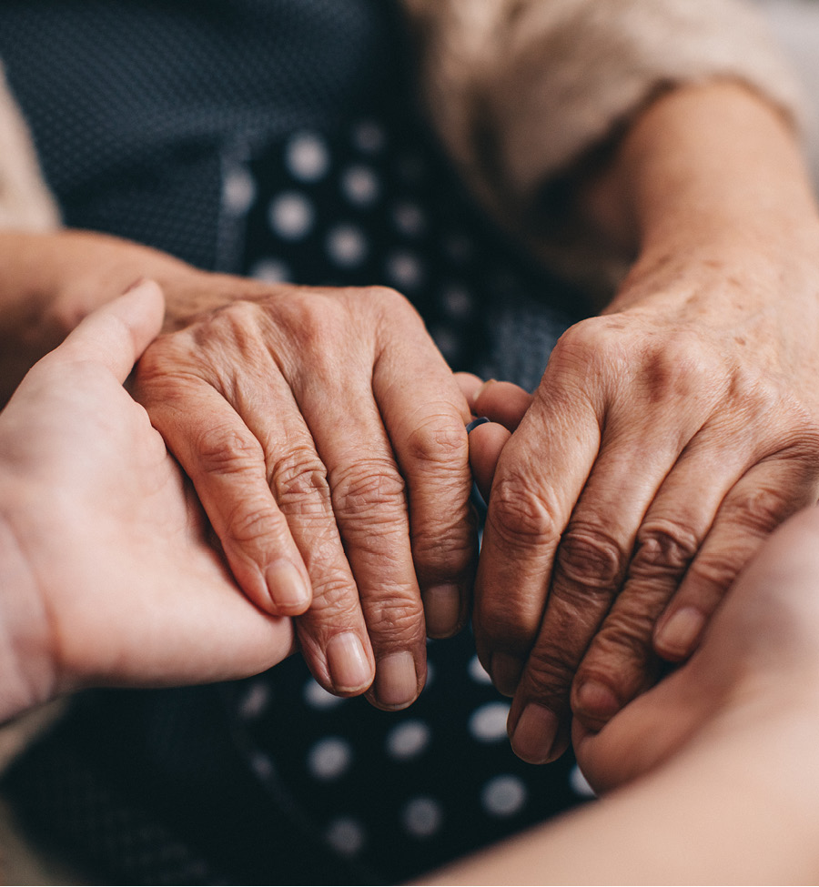 A closeup shot of two people of different races holding hands.