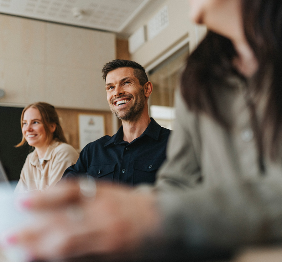 A trio of people sit together at a meeting laughing and smiling.