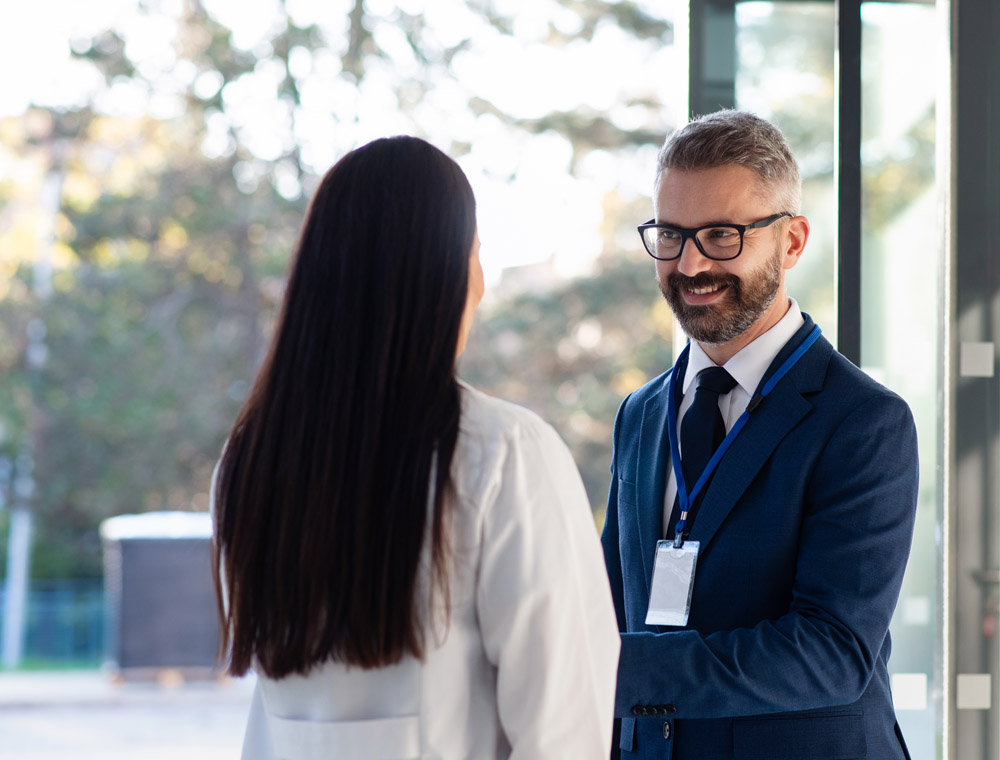 A man and woman exchange handshake during a business conversation.