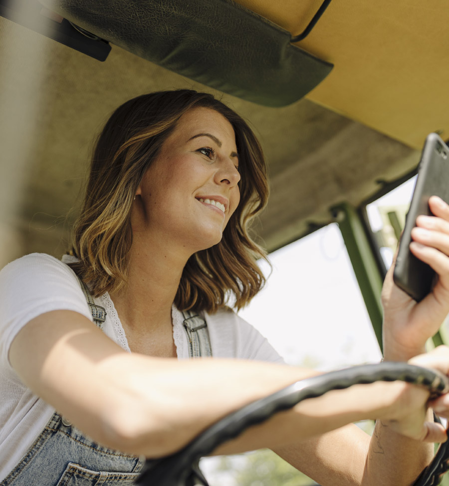 Woman in tractor holding mobile phone