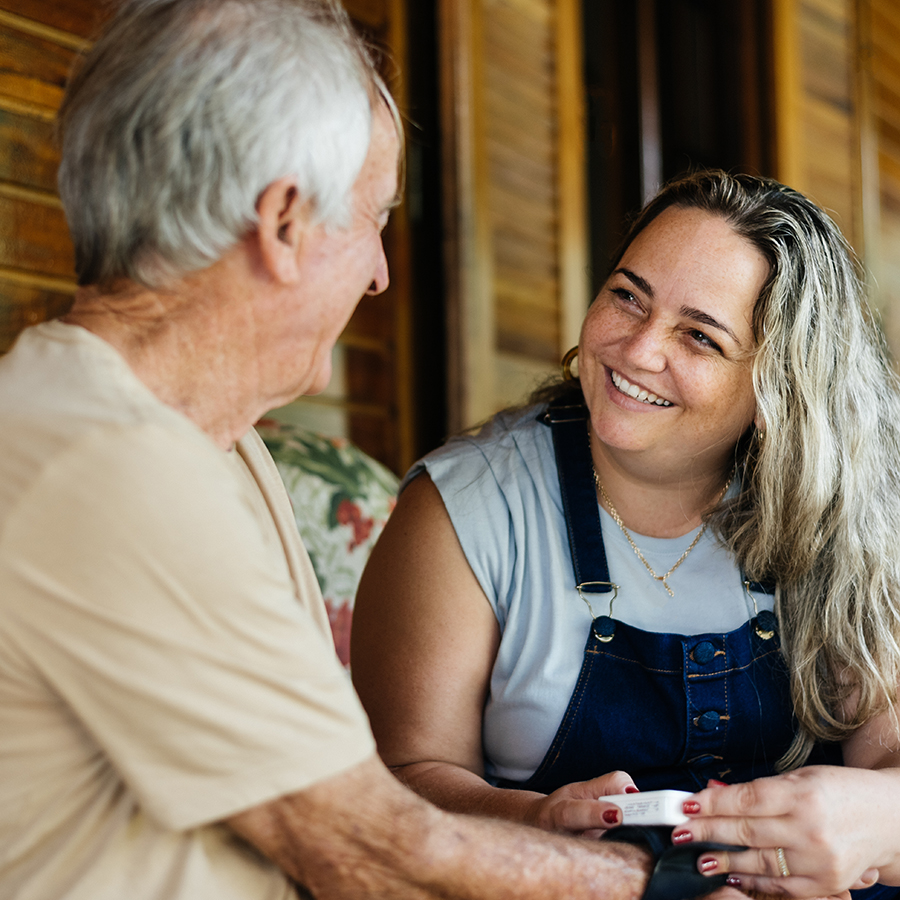 Young woman smiling at elderly man as she offers him assistance.