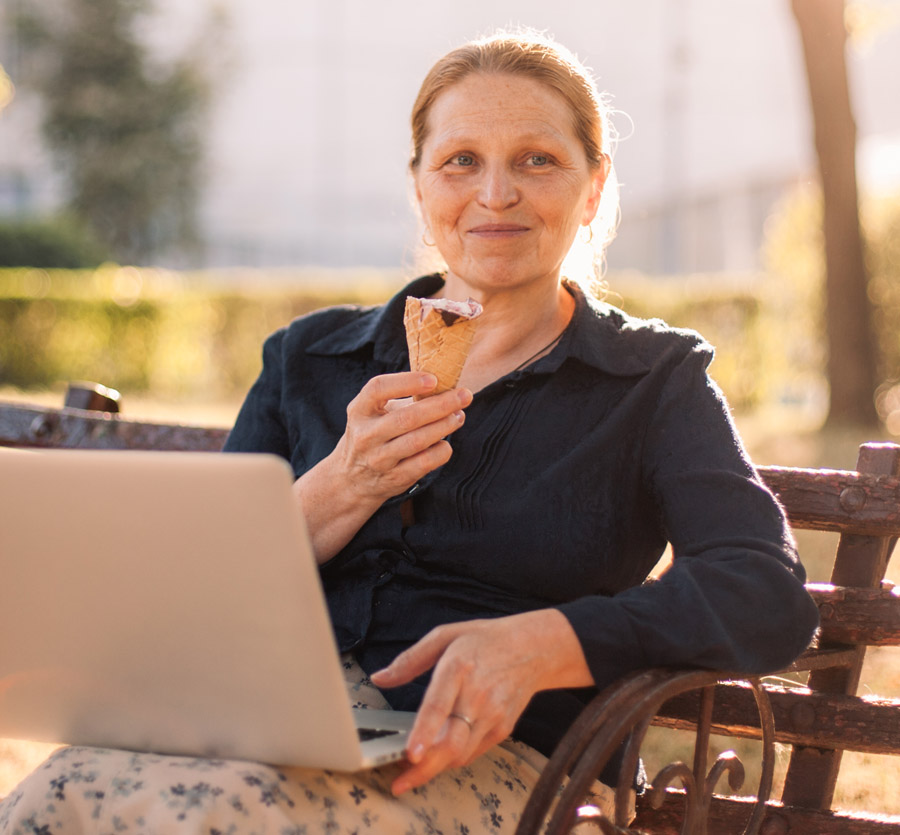 Woman on a bench with computer and ice cream cone